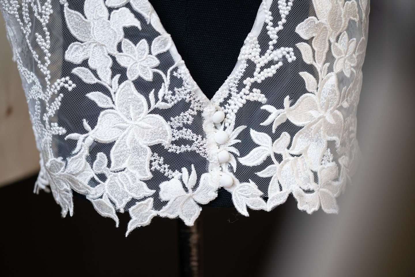 Finition encolure par un biais d’organza et 4 boutons recouverts. Tulle brodé, Stragier.